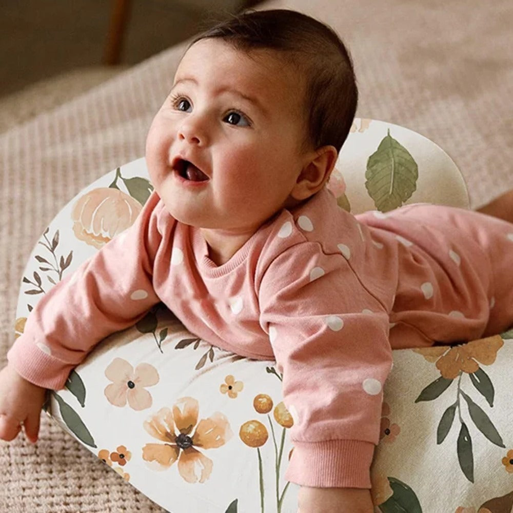 Bébé éveillé sur le ventre, appuyé sur le coussin Fleurs Boréal