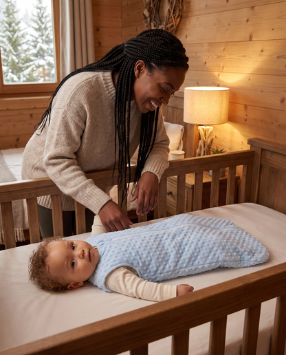 Maman souriant à son bébé couché dans la gigoteuse d'hiver Boréal, chambre de chalet