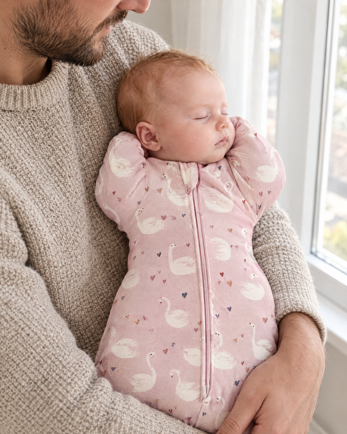 Papa tenant bébé endormi dans la gigoteuse bras levés motif cygnes